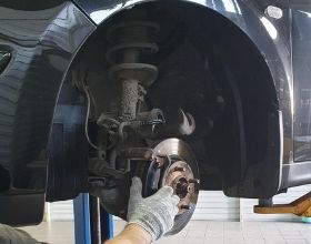 механик обслуживает тормозной диск автомобиля nissan